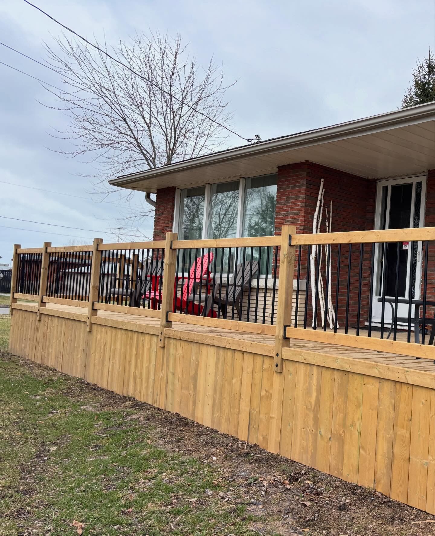 New deck with black metal railings installed at a brick bungalow